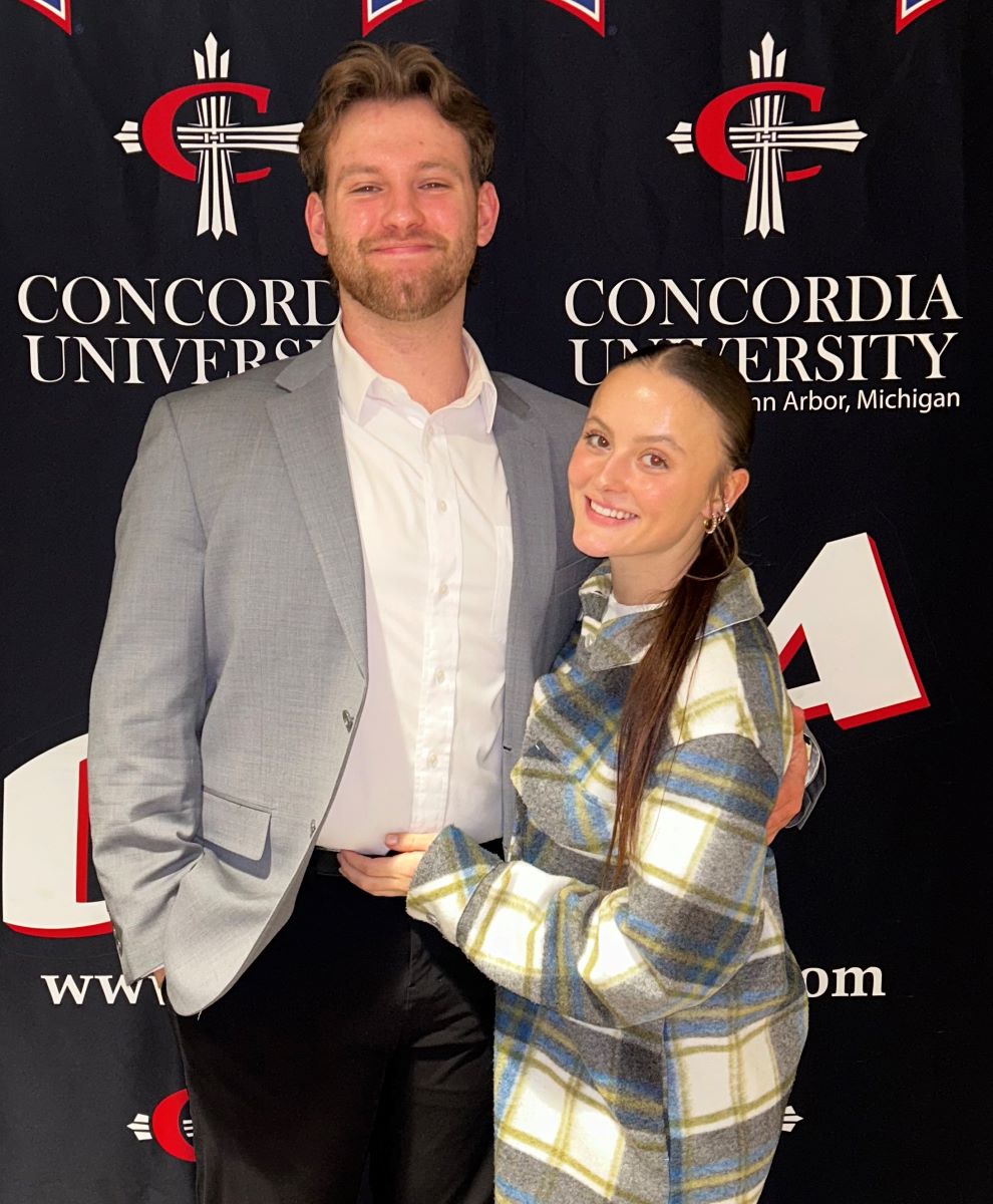 woman and man posing in front of backdrop