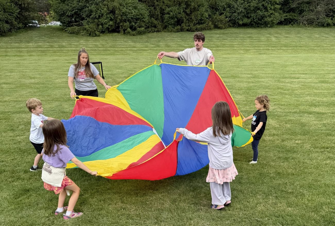 kids and college students with rainbow tarp