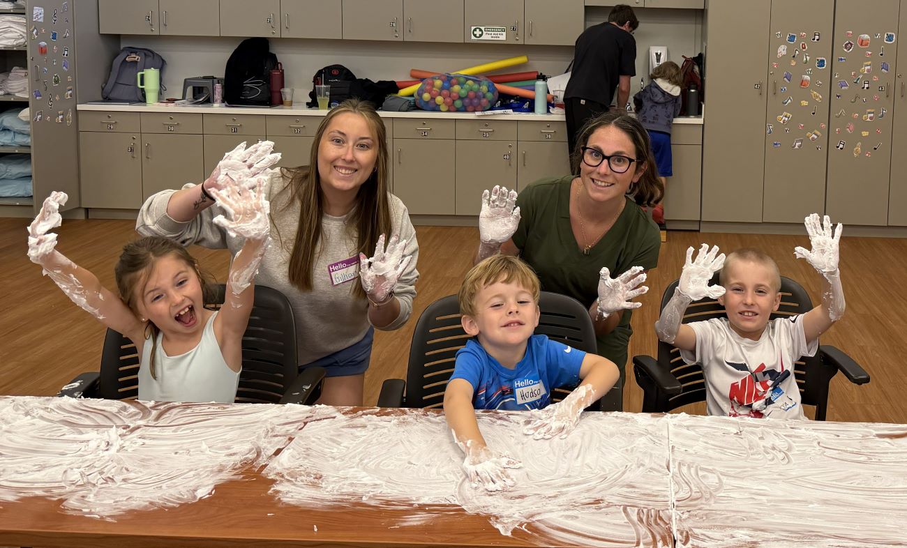 three kids and two students playing with shaving cream