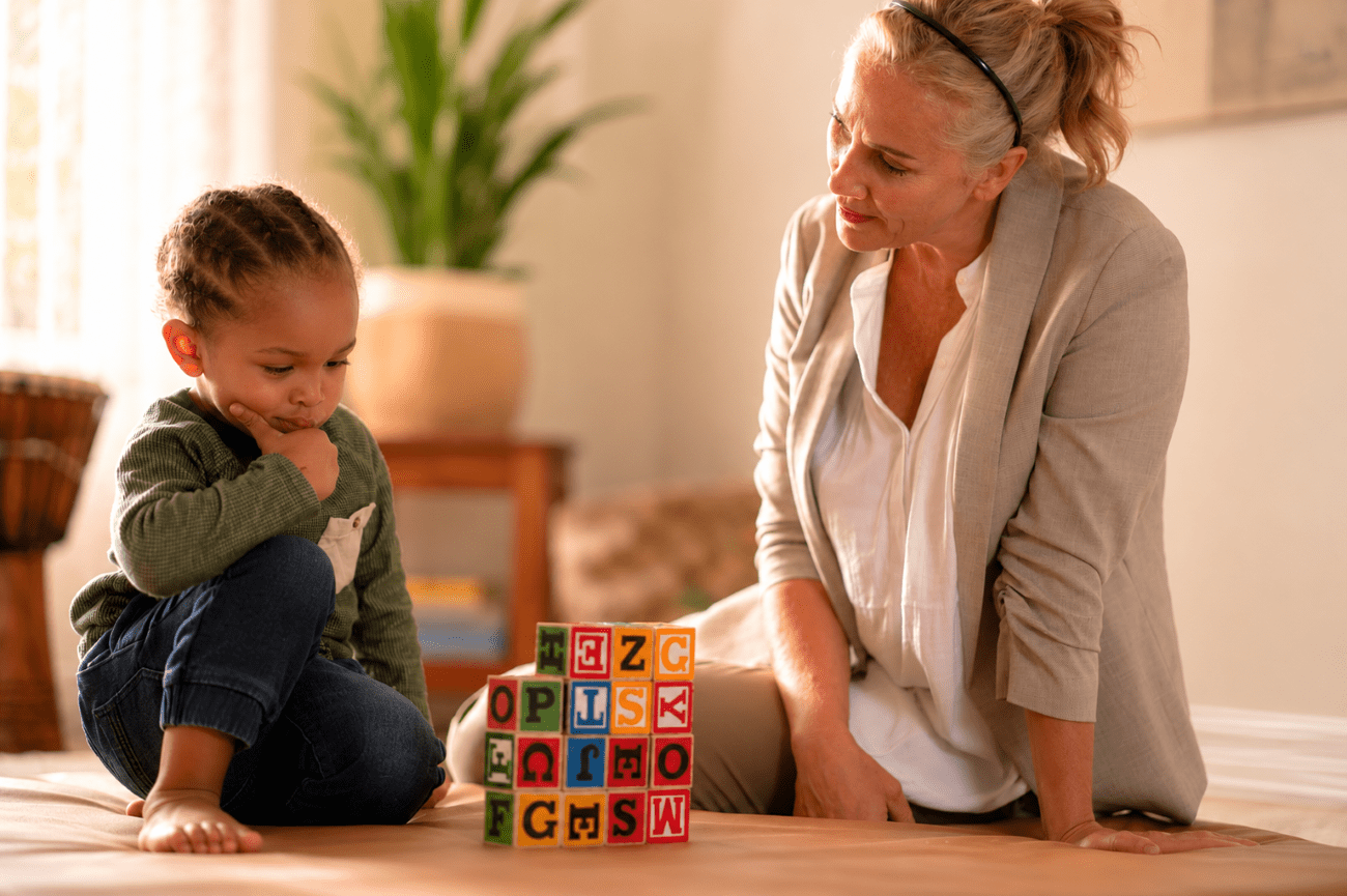woman watching child stack blocks