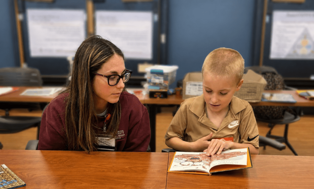kid reading with woman with glasses