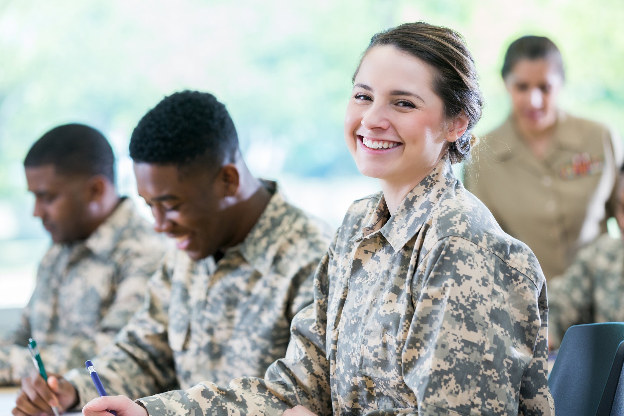 Smiling female cadet attends class at a military academy. She is looking at the camera.